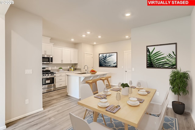 dining area featuring recessed lighting, baseboards, and light wood finished floors