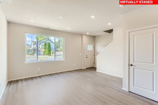 interior space with light wood finished floors, recessed lighting, a textured ceiling, and baseboards