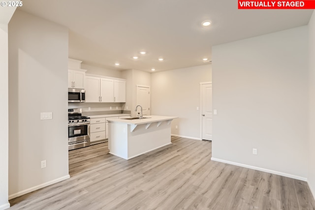 kitchen with light wood finished floors, recessed lighting, appliances with stainless steel finishes, and a sink