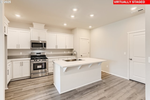 kitchen featuring visible vents, a sink, stainless steel appliances, light wood-style floors, and light countertops