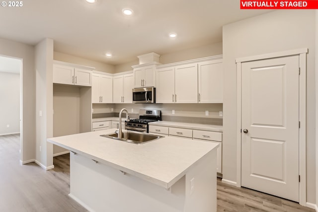 kitchen with light wood-style flooring, a sink, recessed lighting, appliances with stainless steel finishes, and white cabinets