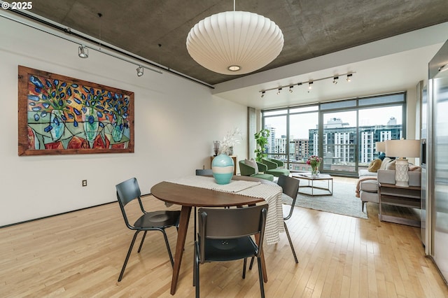 dining room with track lighting, light wood-type flooring, and a city view