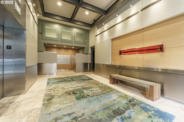 corridor featuring a towering ceiling, elevator, coffered ceiling, beam ceiling, and recessed lighting