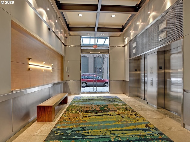 hallway with coffered ceiling, a high ceiling, beamed ceiling, elevator, and recessed lighting