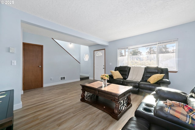 living area featuring visible vents, a textured ceiling, baseboards, and wood finished floors