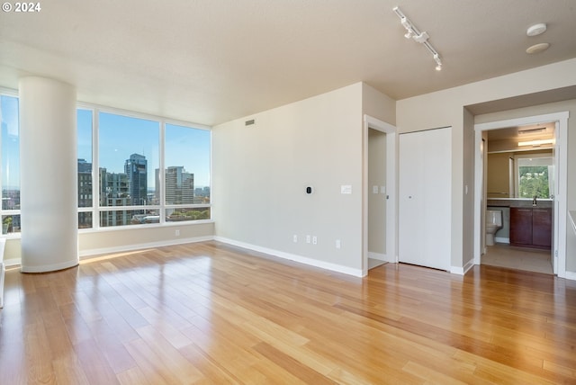 1500 SW 11th Ave Unit 1703, Portland, OR 97201 - unfurnished room featuring a wealth of natural light, baseboards, a city view, and light wood finished floors