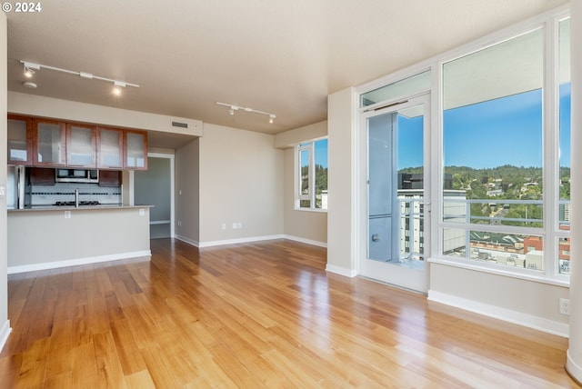 1500 SW 11th Ave Unit 1703, Portland, OR 97201 - unfurnished living room with visible vents, baseboards, light wood-type flooring, rail lighting, and a sink