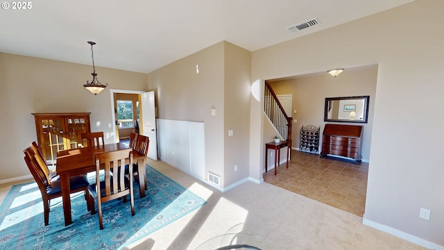 carpeted dining space with visible vents, baseboards, and stairway