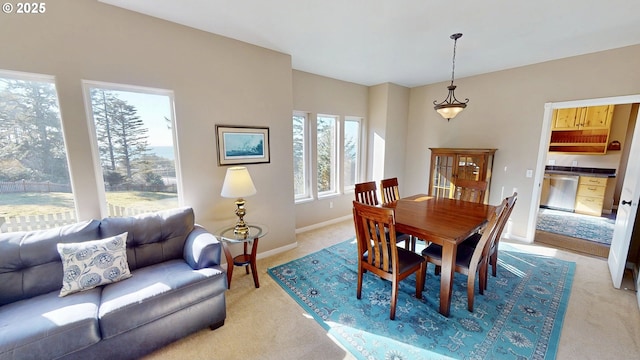 dining space featuring light colored carpet and baseboards