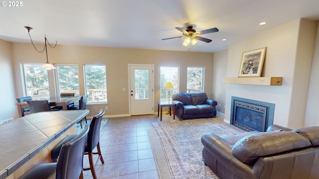 living area featuring baseboards, a fireplace with flush hearth, light tile patterned floors, recessed lighting, and a ceiling fan