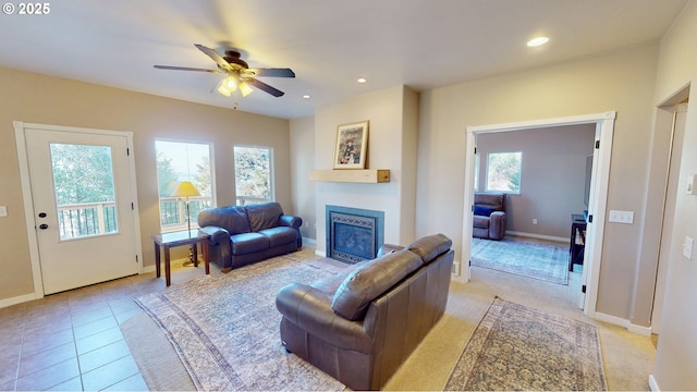 living room with light tile patterned floors, a glass covered fireplace, recessed lighting, and ceiling fan