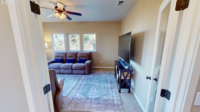 living room with visible vents, baseboards, light carpet, and a ceiling fan