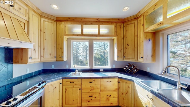 kitchen featuring light brown cabinetry, a sink, custom range hood, and range