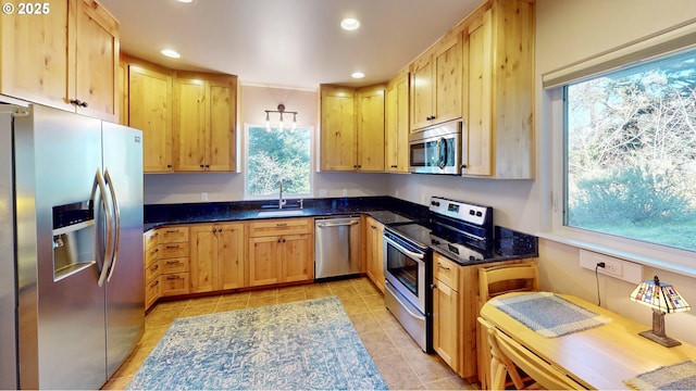 kitchen featuring light brown cabinetry, dark stone counters, recessed lighting, stainless steel appliances, and a sink