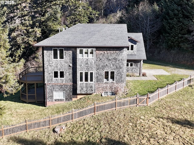 view of side of property featuring a lawn, fence, and a shingled roof