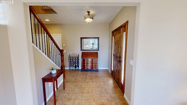 entrance foyer with light tile patterned floors, stairway, and baseboards