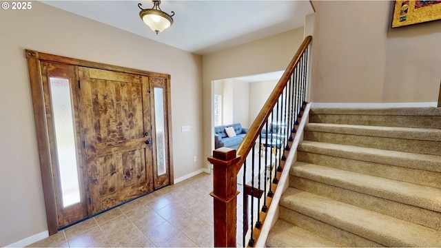 entrance foyer with light tile patterned flooring, plenty of natural light, stairway, and baseboards