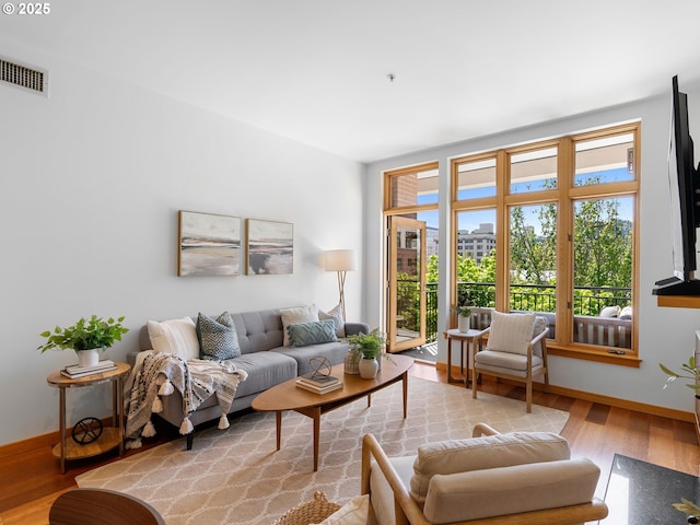 living area featuring baseboards, visible vents, and wood finished floors