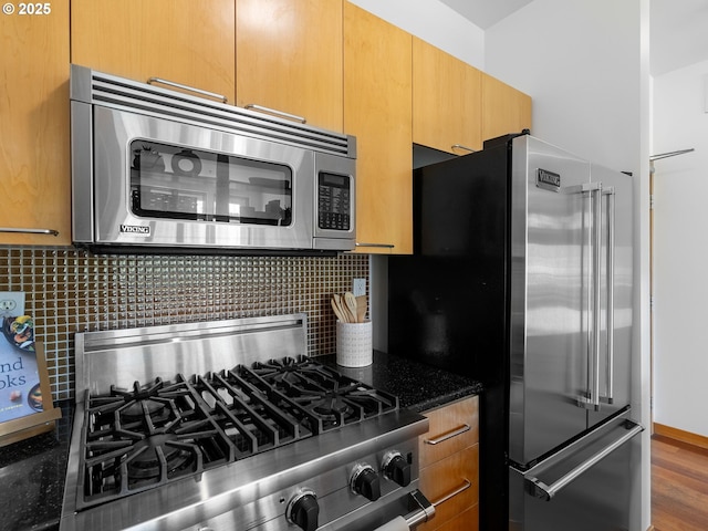 kitchen featuring backsplash, high quality appliances, and dark stone counters