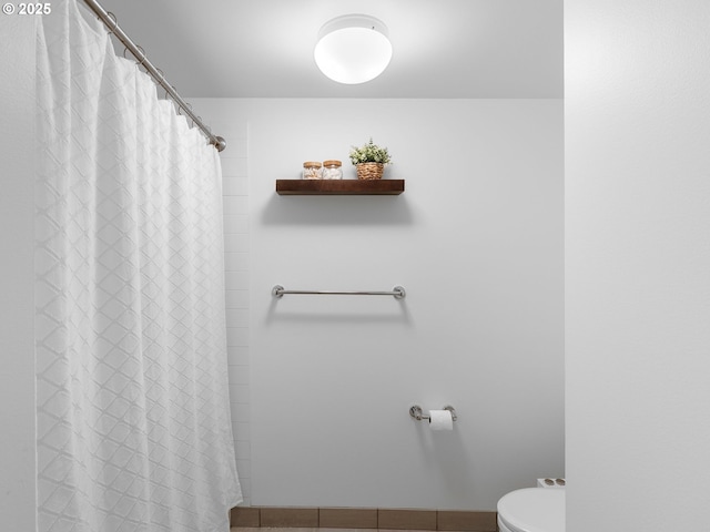 full bath featuring baseboards, toilet, tile patterned floors, and a shower with shower curtain