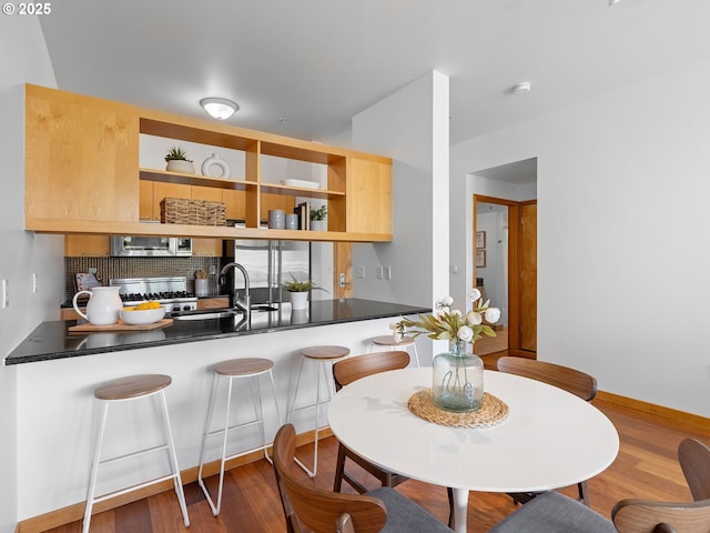 kitchen featuring open shelves, wood finished floors, dark countertops, appliances with stainless steel finishes, and backsplash