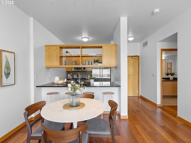 dining area featuring visible vents, baseboards, and wood finished floors