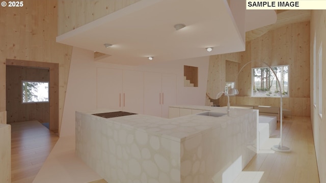 kitchen featuring a healthy amount of sunlight, white cabinets, light wood-style flooring, and a sink