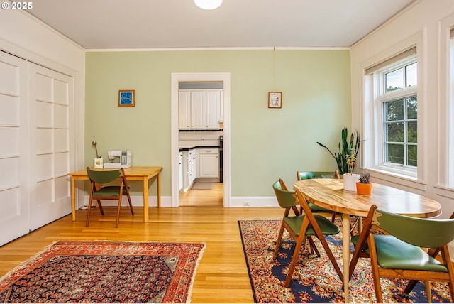 dining room with light wood-type flooring, crown molding, and baseboards