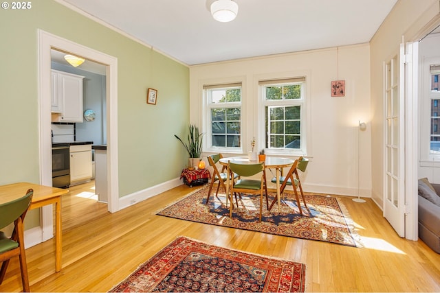 dining room featuring ornamental molding, light wood-style flooring, and baseboards