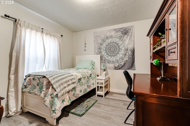 bedroom with a textured ceiling and light wood-type flooring