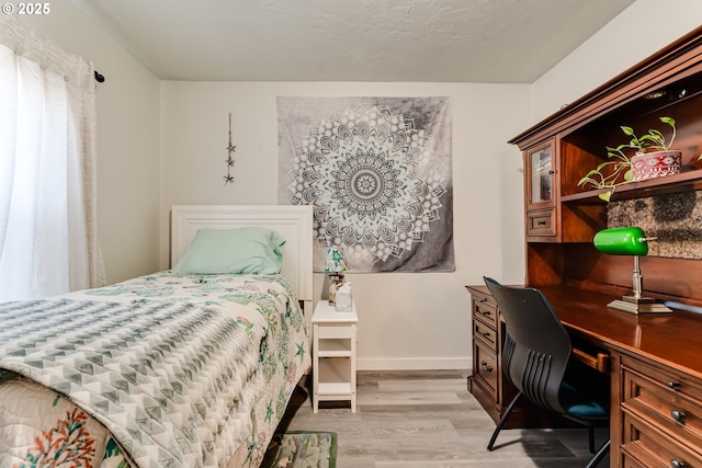 bedroom featuring light hardwood / wood-style flooring and a textured ceiling