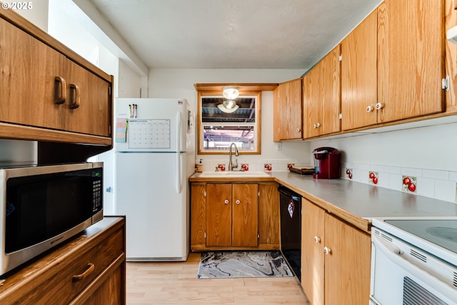 kitchen featuring sink, white appliances, decorative backsplash, and light wood-type flooring