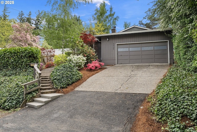 view of front of house featuring a garage, driveway, and a chimney