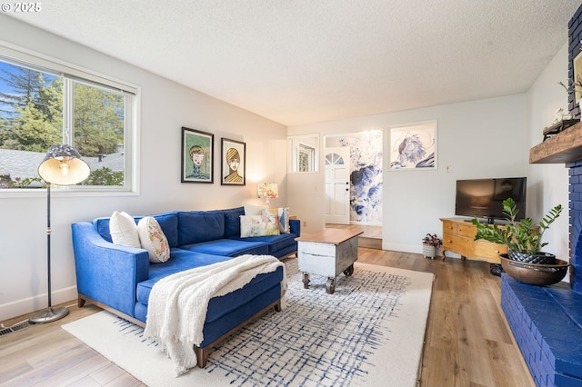 living area with a textured ceiling, baseboards, wood finished floors, and visible vents