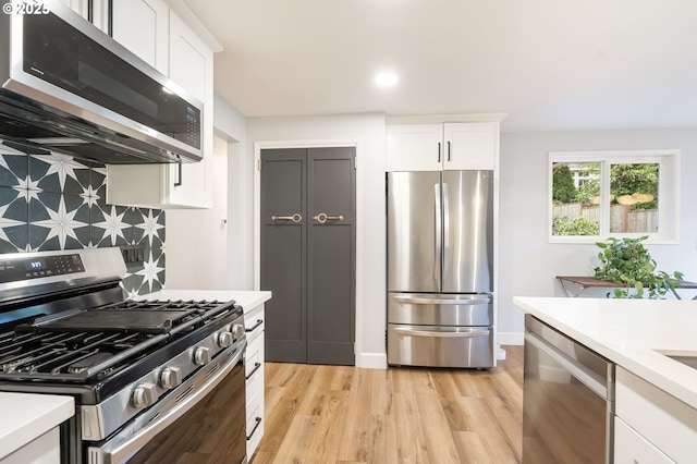 kitchen featuring light wood-type flooring, light countertops, white cabinets, backsplash, and stainless steel appliances
