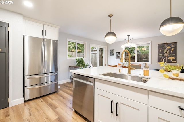 kitchen featuring light countertops, hanging light fixtures, appliances with stainless steel finishes, and a sink