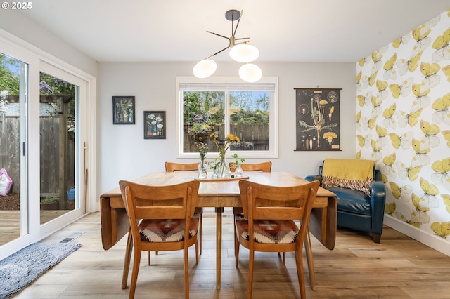 dining space with light wood-style flooring and a notable chandelier