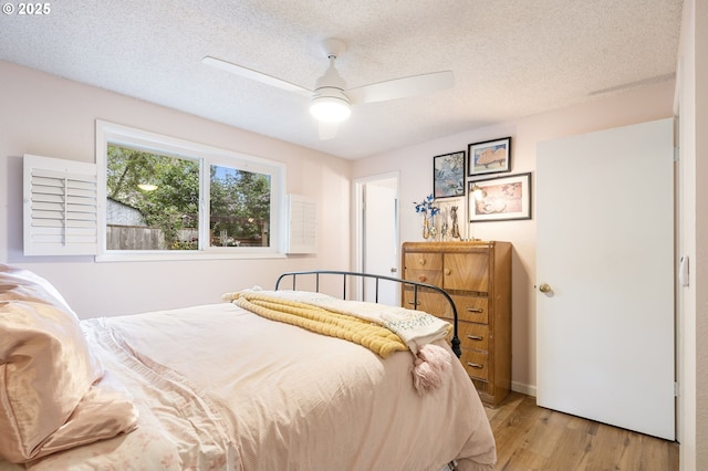 bedroom featuring a ceiling fan, light wood-style flooring, and a textured ceiling