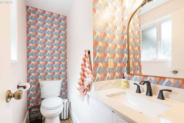 bathroom featuring toilet, wallpapered walls, and vanity