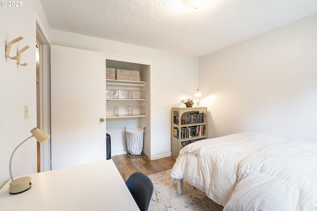 bedroom with a textured ceiling and wood finished floors