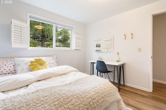 bedroom with baseboards and wood finished floors