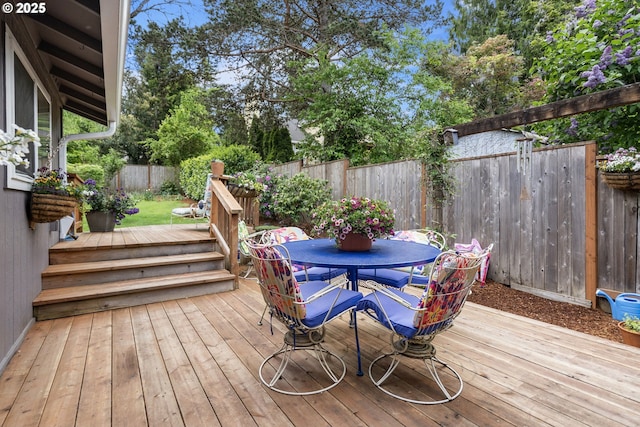 wooden terrace with a fenced backyard and outdoor dining space