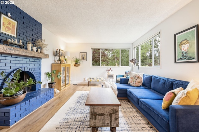 living area featuring a brick fireplace, a textured ceiling, and wood finished floors