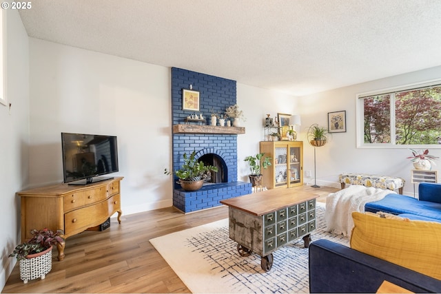 living area with baseboards, a textured ceiling, a brick fireplace, and wood finished floors