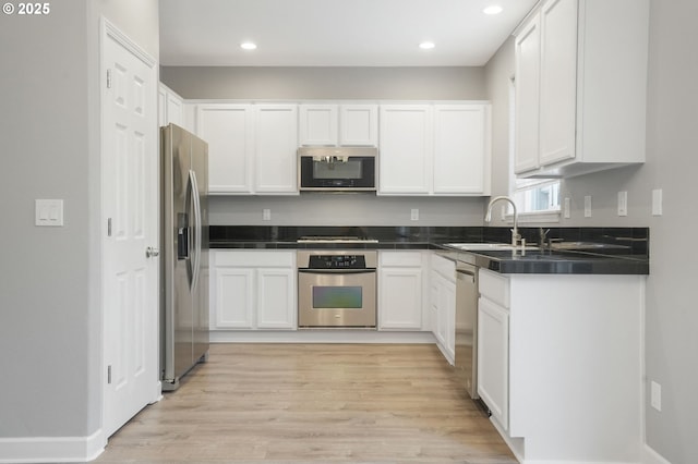 kitchen with white cabinetry, appliances with stainless steel finishes, sink, and light hardwood / wood-style flooring