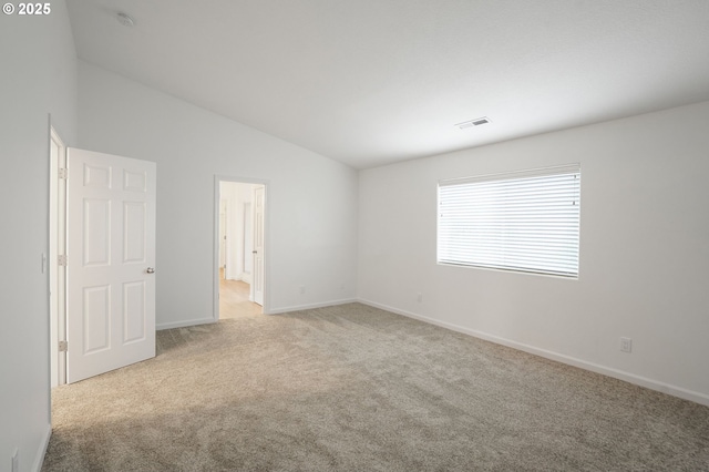 unfurnished room featuring light carpet and vaulted ceiling