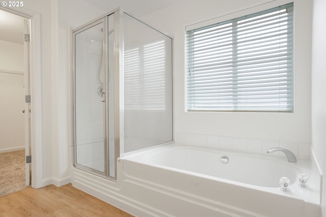 bathroom featuring a wealth of natural light, shower with separate bathtub, and wood-type flooring