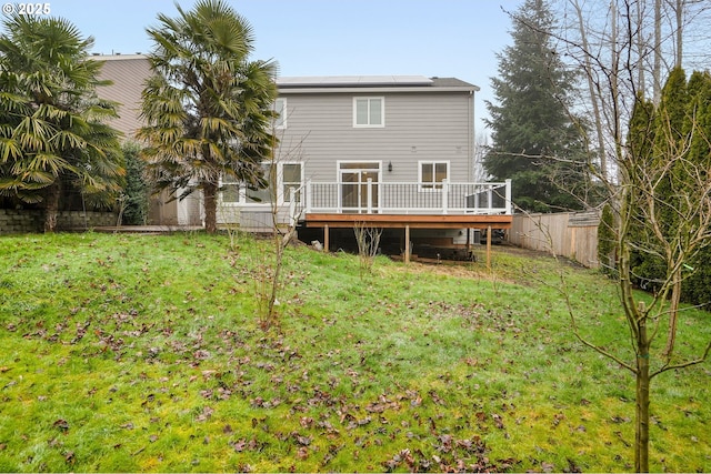 back of house with a lawn, solar panels, and a deck