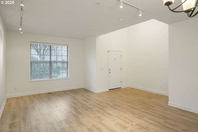 spare room featuring track lighting and light hardwood / wood-style flooring