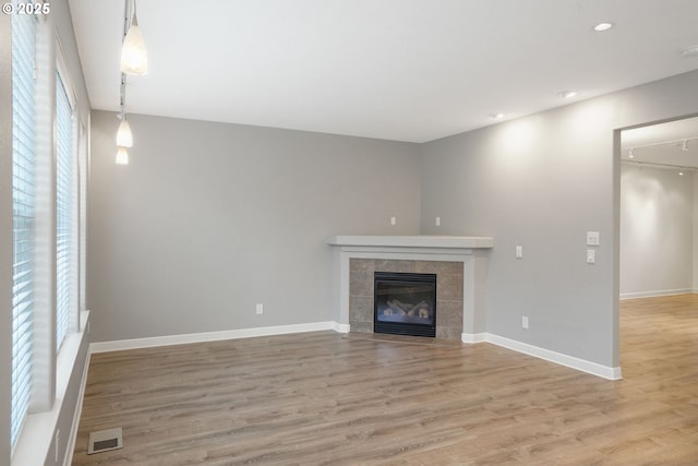 unfurnished living room featuring a tiled fireplace and wood-type flooring